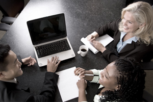 A group of people sitting around a laptop